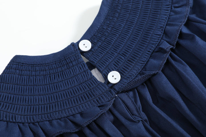Navy blue Blue Nativity Smocked Ruffle Romper with pleated textured collar and two white buttons at the back; size 3-6M.