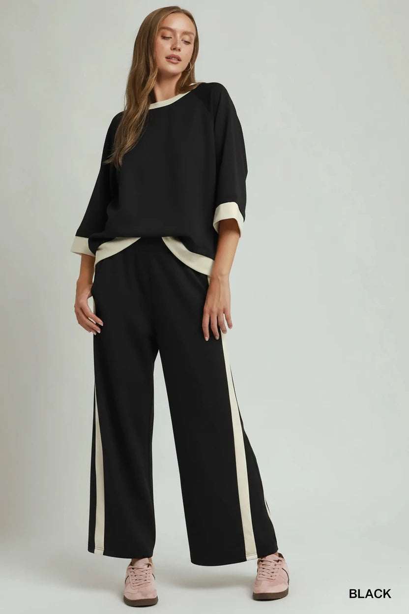 Black colorblock side striped straight pants in a luxe knit with wide cream-colored trim on the pant sides; available in sizes XS-XL.