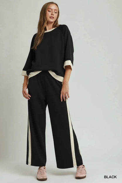 Black colorblock side striped straight pants in a luxe knit with wide cream-colored trim on the pant sides; available in sizes XS-XL.