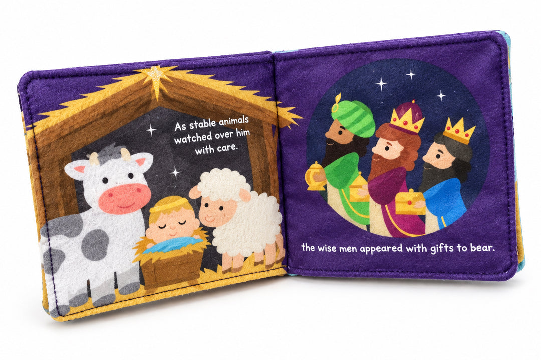 The First Christmas Soft Book open to a nativity scene showing baby Jesus, a cow, a sheep, and three wise men with gifts.