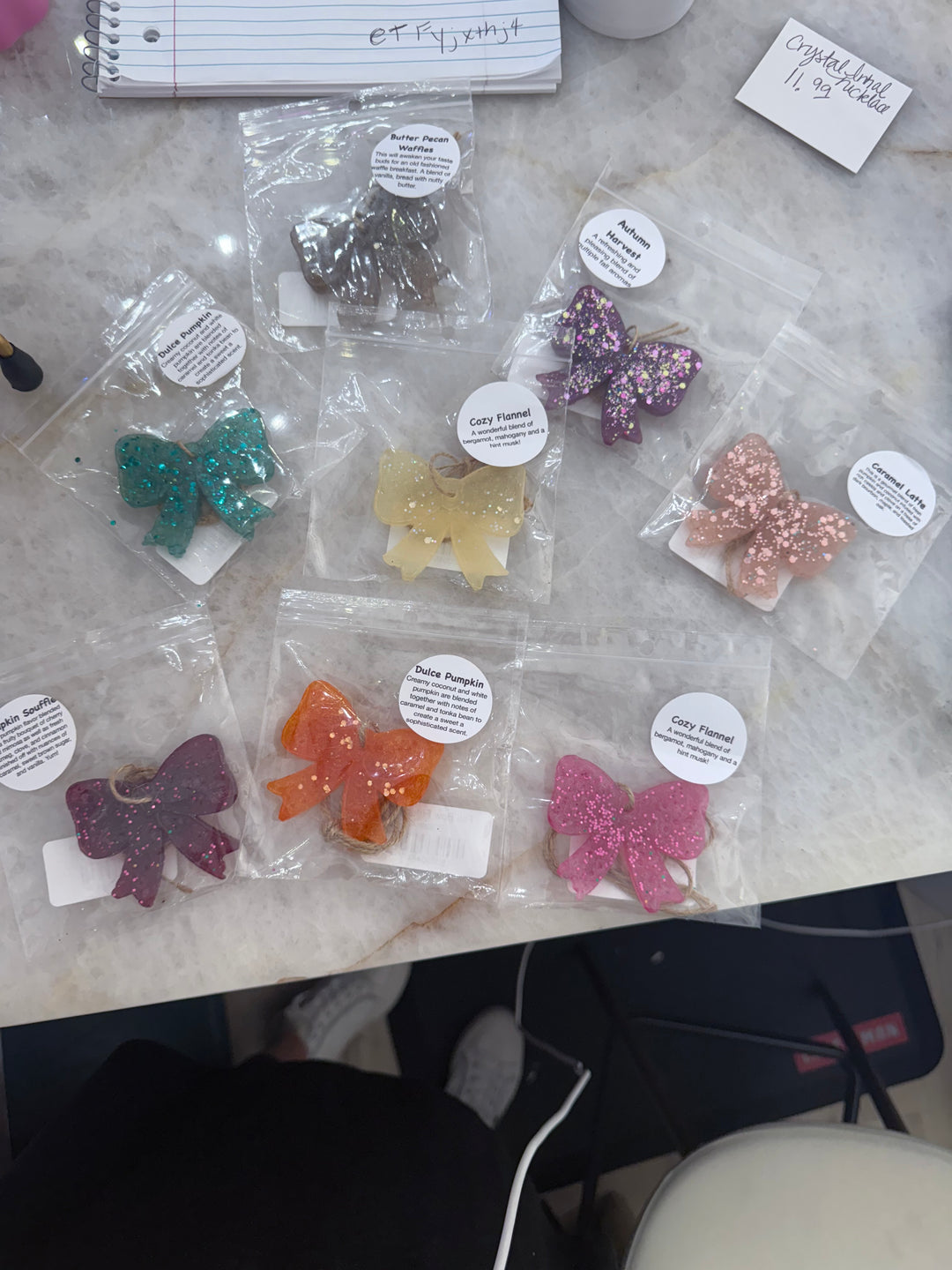 Bow Freshies, vibrant and glittery scented wax decor, in clear bags with round white labels; available in small and large sizes.