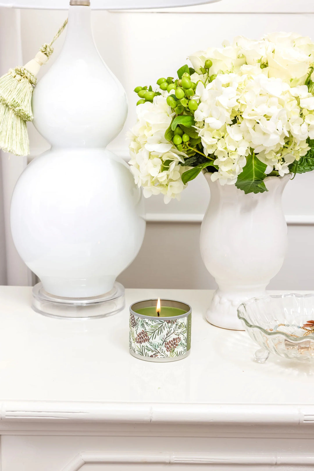 Lit 4oz Silver Spruce candle in a tin with green pine cone and branch pattern. Available in 4oz.