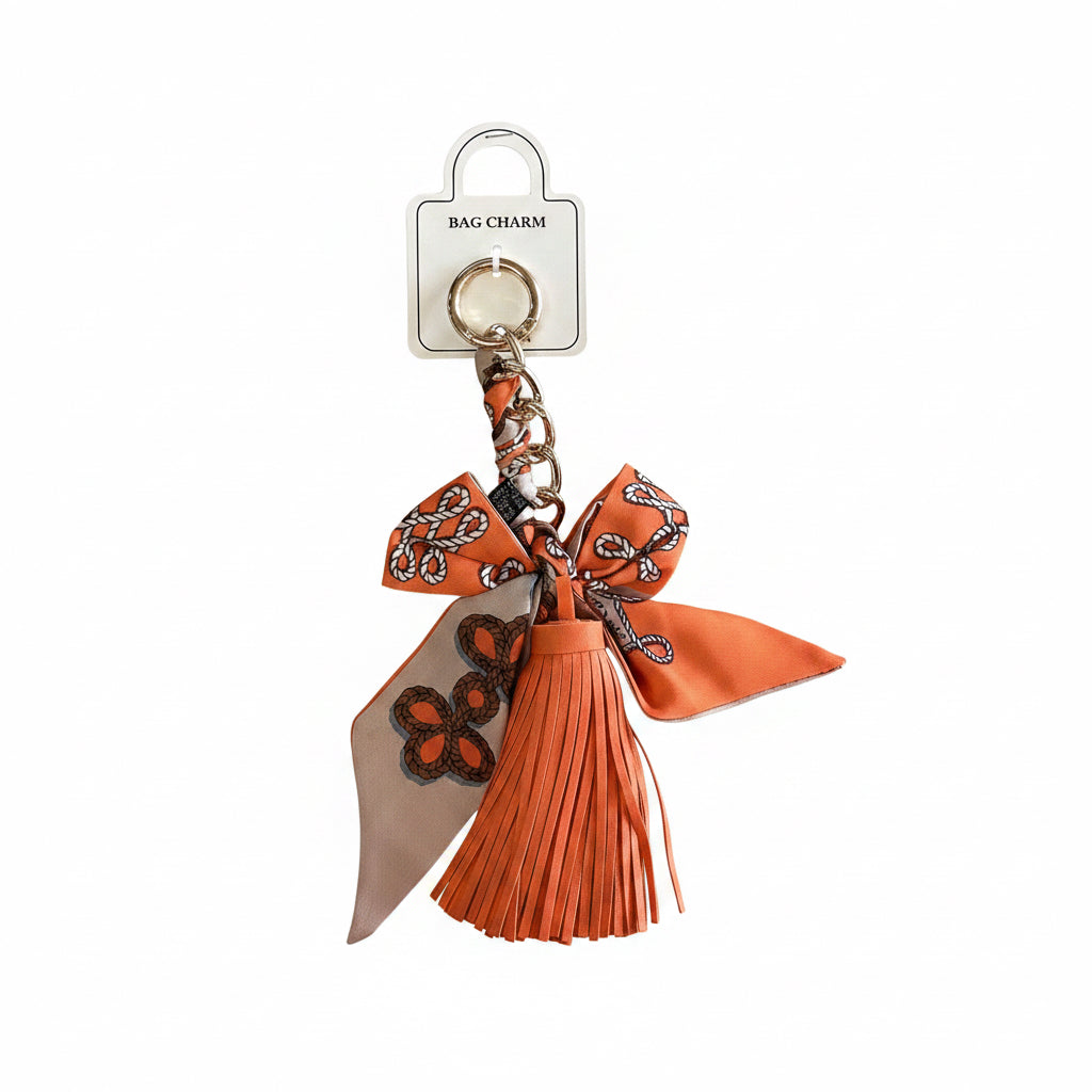 Vibrant orange tassel with butterfly-patterned ribbon and metal ring. Sizes available: small, medium, large.