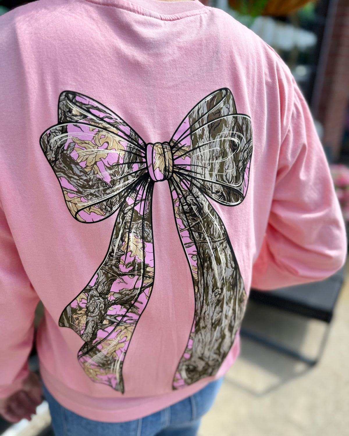Pink cotton long sleeve shirt with large tree camo bow design on the back; available in sizes S-XL.