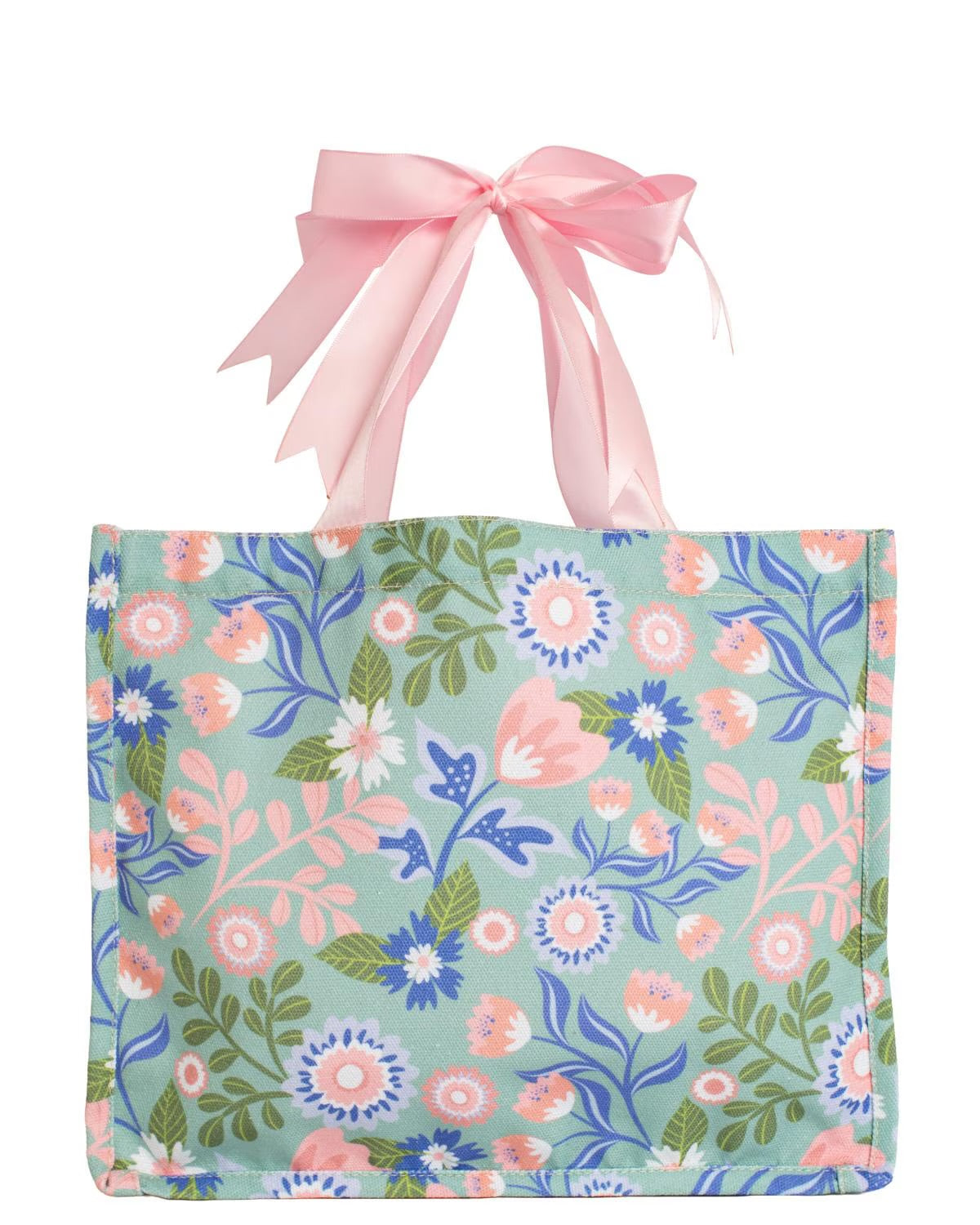 The Lizzie Floral Gift Tote Bag features a vibrant pink, blue, and green pattern with pink bow handles; available in multiple sizes.