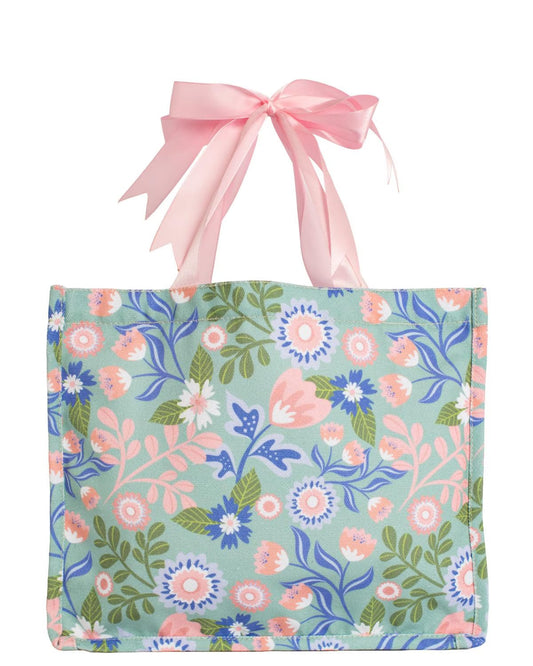 The Lizzie Floral Gift Tote Bag features a vibrant pink, blue, and green pattern with pink bow handles; available in multiple sizes.