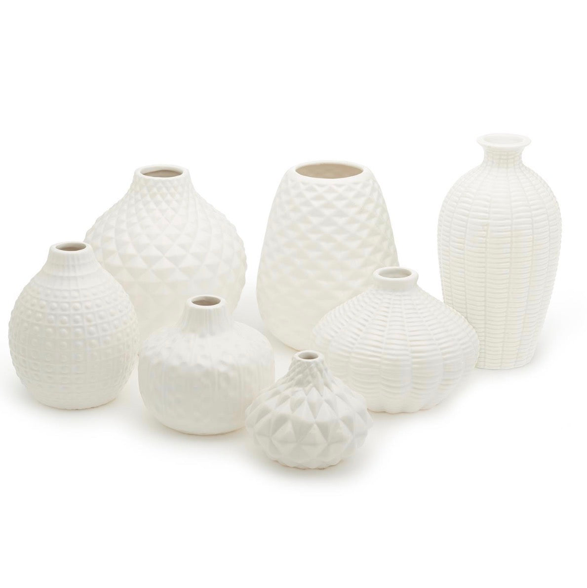 White ceramic vases with unique artisan-carved geometric patterns, available in seven distinct shapes and sizes.