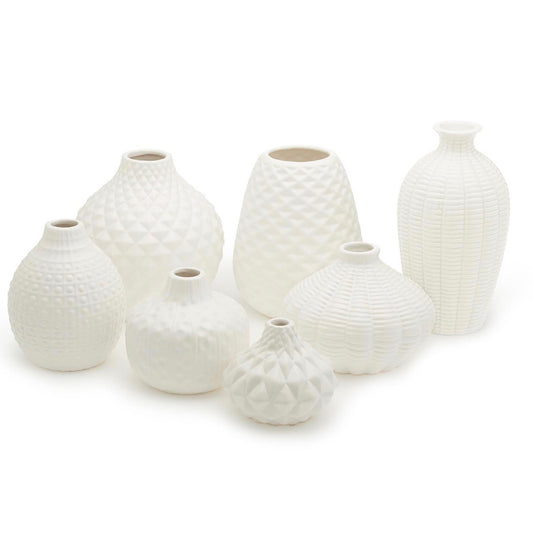 White ceramic vases with unique artisan-carved geometric patterns, available in seven distinct shapes and sizes.