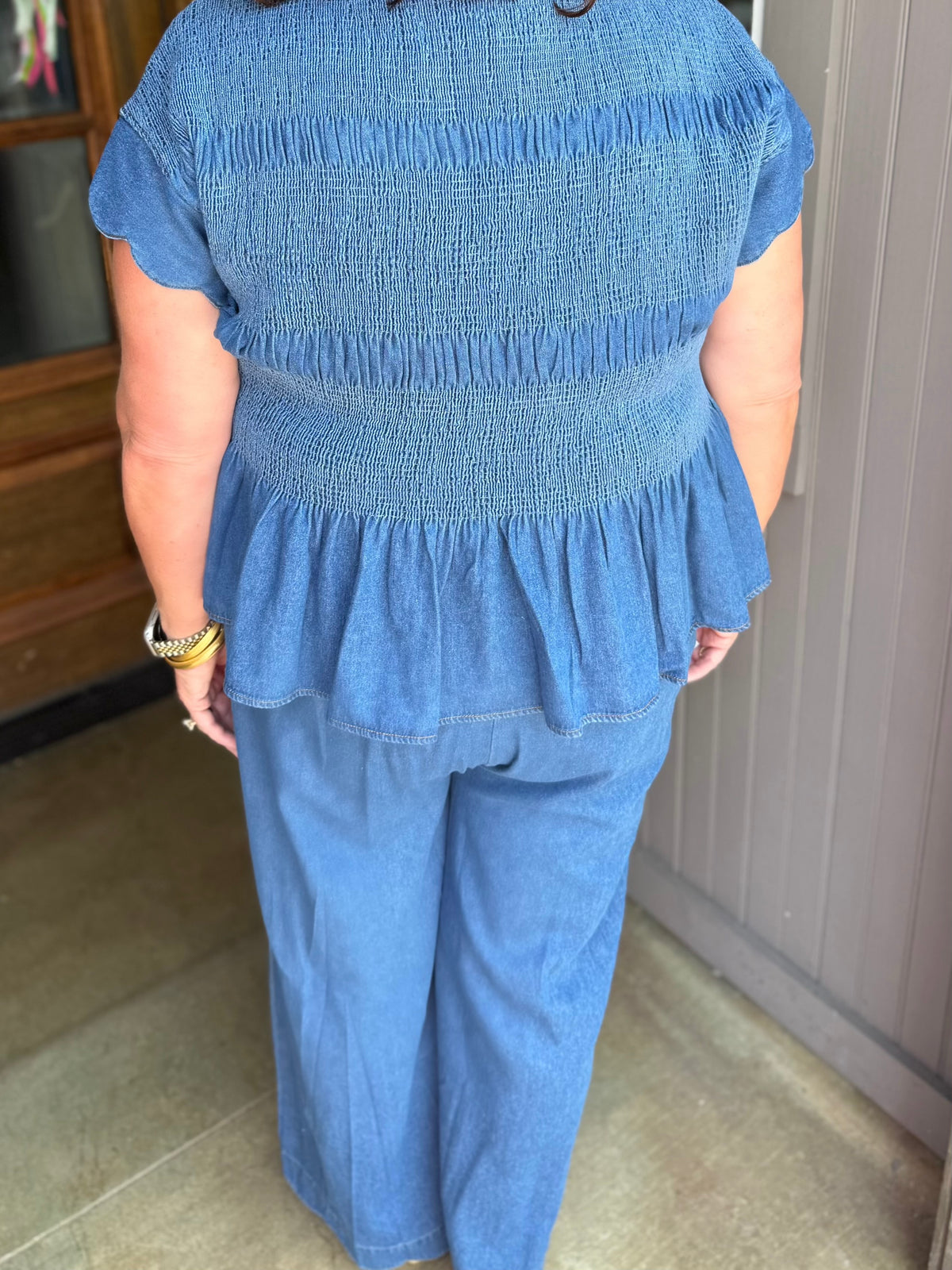 Blue short-sleeve smocked top with ruffled hem, available in sizes XS-XL.