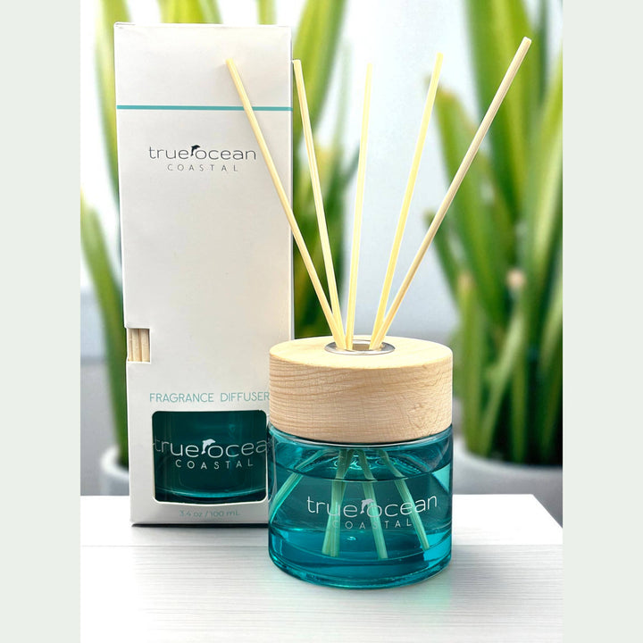 Blue glass True Ocean Reed Diffuser with wooden sticks. Available in 100ml and 200ml sizes; features ocean-inspired scent.