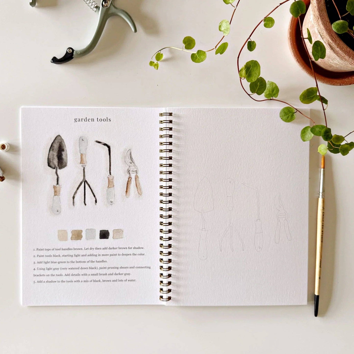 The Garden Watercolor Workbook open to garden tool illustrations and outlines for practice. Available in 8x10 and 9x12 inches.
