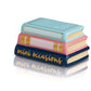 A stack of three ceramic books titled "Book and Mini Book w/Mini" showcasing "mini occasions" in gold lettering on the spine of the bottom book. Designed by Nora Fleming, these pastel-colored books feature light blue, peach, and navy hues. Available sizes: N/A (decorative set only).