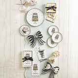 Decorative cookies shaped like bows, cakes, and tags topped with black, white, and gold icing; some finished with ribbon accents. Available in multiple sizes.