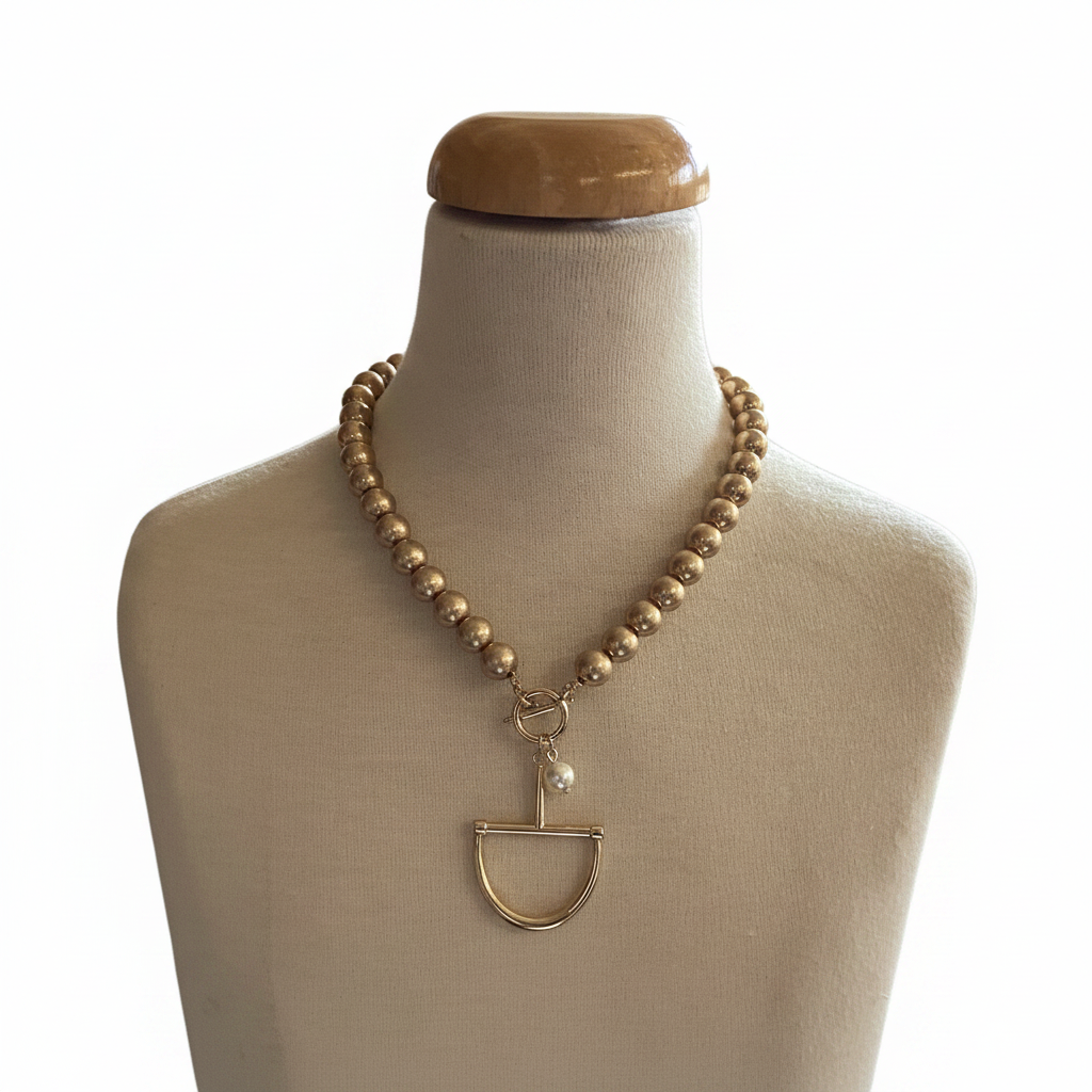 The Fud Gold Pearl Necklace features a gold beaded chain, geometric pendant, and delicate pearl. Available in 16″, 18″, and 20″ lengths.