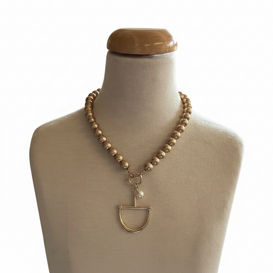 The Fud Gold Pearl Necklace features a gold beaded chain, geometric pendant, and delicate pearl. Available in 16″, 18″, and 20″ lengths.