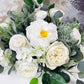 A vibrant floral arrangement with lifelike Real Touch Orlane Rose (15" long) in pure white, peonies, and greenery including eucalyptus and broad leaves. Features lush blossoms with yellow stamens.