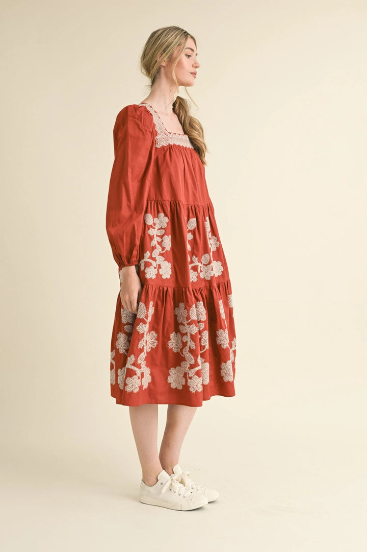 Rust tiered midi dress with square neckline and white floral embroidery. Available in all sizes.