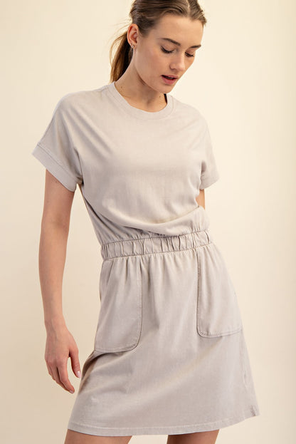 Mineral Washed Elastic Waist Cotton Dress: Light beige mini dress featuring a relaxed silhouette, elastic waistband, and large front pockets. Available in sizes S, M, L.
