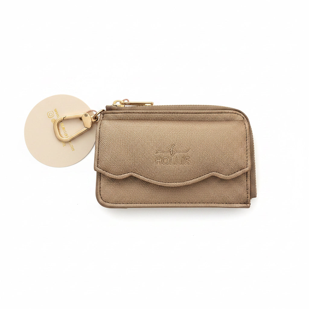 Small gold-colored Hollis Scalloped Cardholder with zipper closure, scalloped front pocket, gold keyring clip, round tag, “HOLLIS” and bird emblem embossed on front. Available in one size.