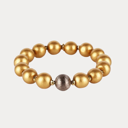 Shaanti Bracelet with eleven polished gold beads and one textured silver bead on a stretchy band; handcrafted in the USA; available sizes not specified.