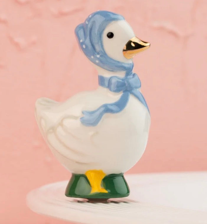 The 80s Goose Porch Pal is a ceramic figurine with a blue bonnet, ribbon, green shoes, and gold-tipped beak. Available sizes: small (6″), medium (10″), large (14″).