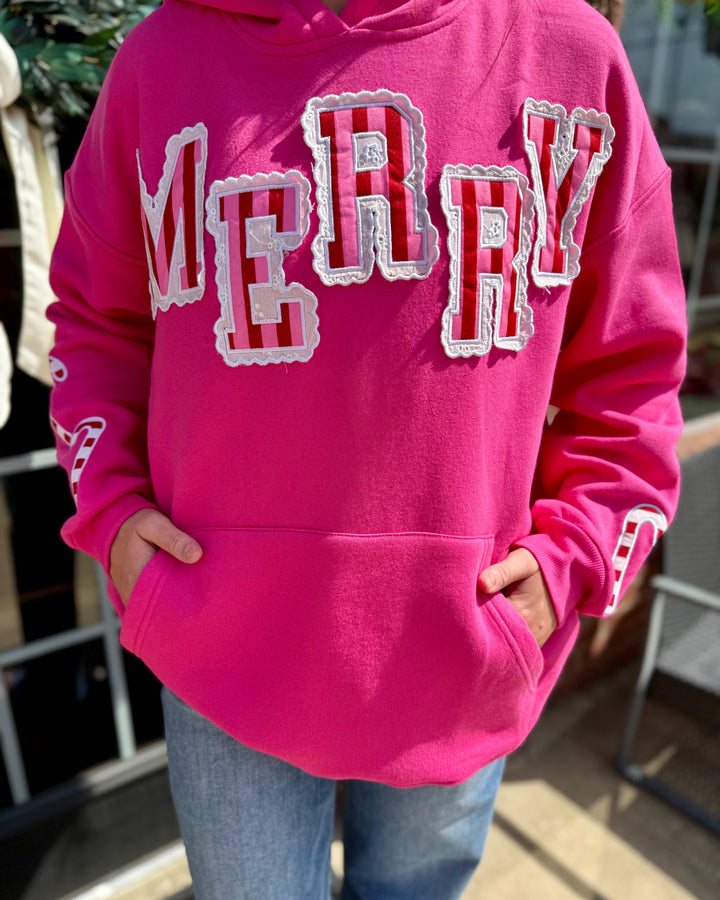 Bright pink Striped Scallop Merry Hoodie with bold “MERRY” letters and a front pocket. Available in sizes XS-XXL.