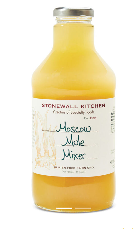 Clear glass bottle labeled "Moscow Mule 24 oz. Mixer" with yellow-orange liquid, metal cap, and hand-drawn ginger on label.