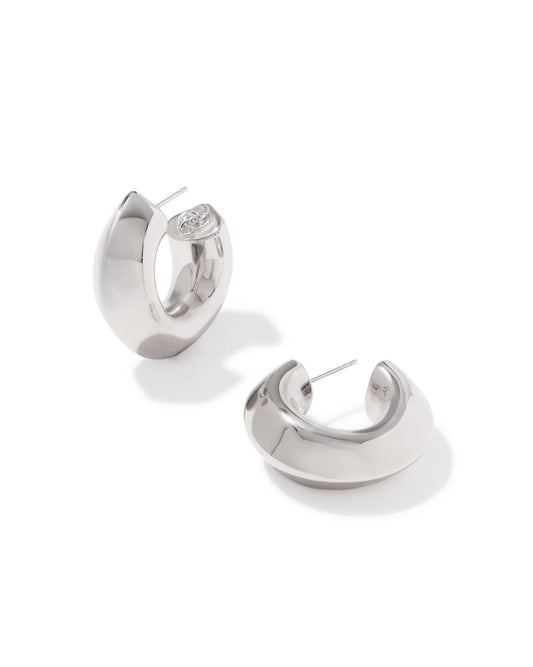 Bold, chunky silver-tone hoop earrings with a polished finish; one features a classic post backing, the other has a small decorative emblem on the inner curve. Available in multiple sizes.
