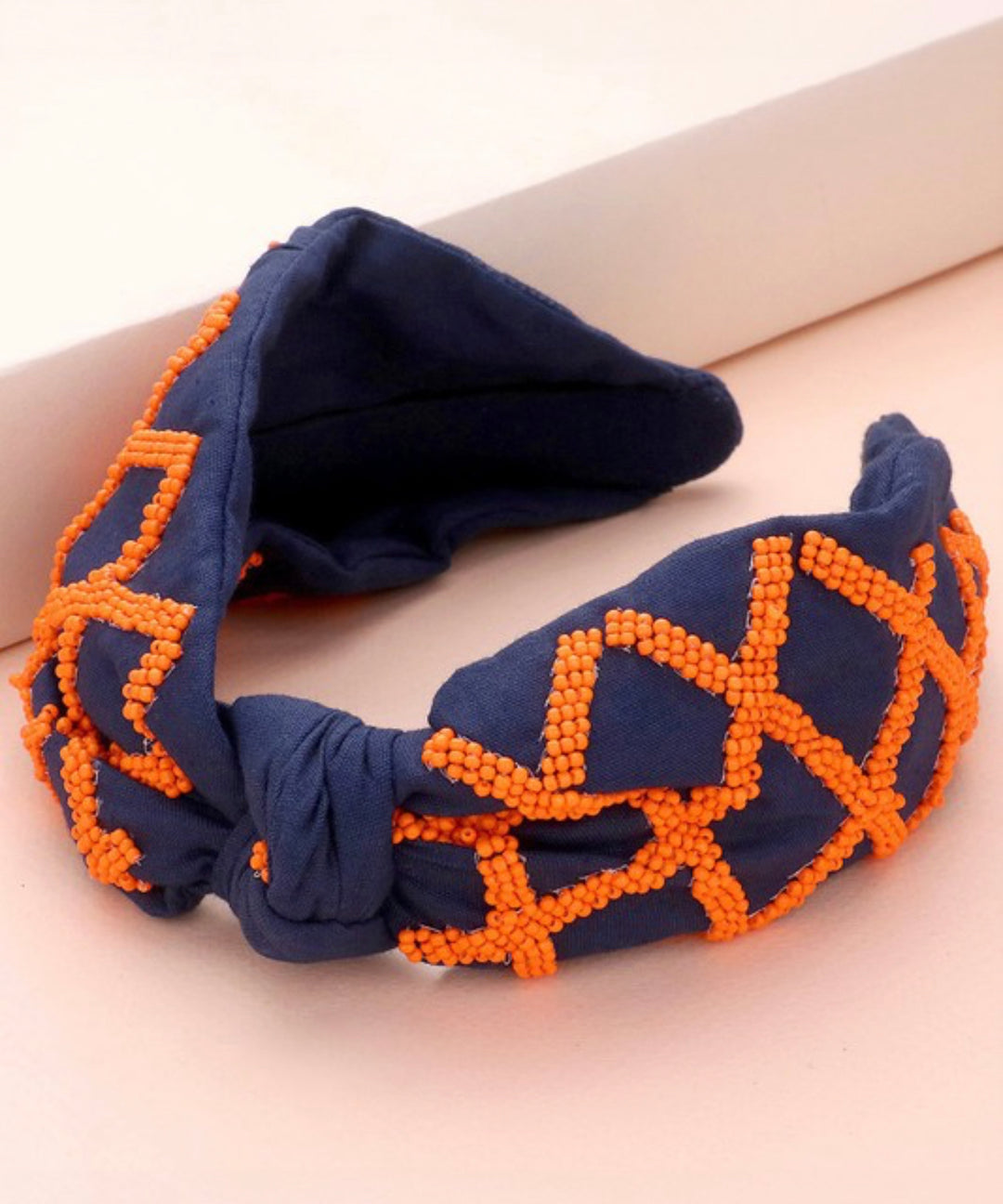 Navy blue Game Day Seed Beaded Check Knot Headband with bright orange geometric patterns. Available in one size.