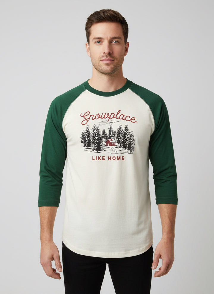 Men’s Snow Place Like Home Baseball T-Shirt in cream with green three-quarter sleeves, featuring a snowy cabin graphic and “Snowplace LIKE HOME” text.