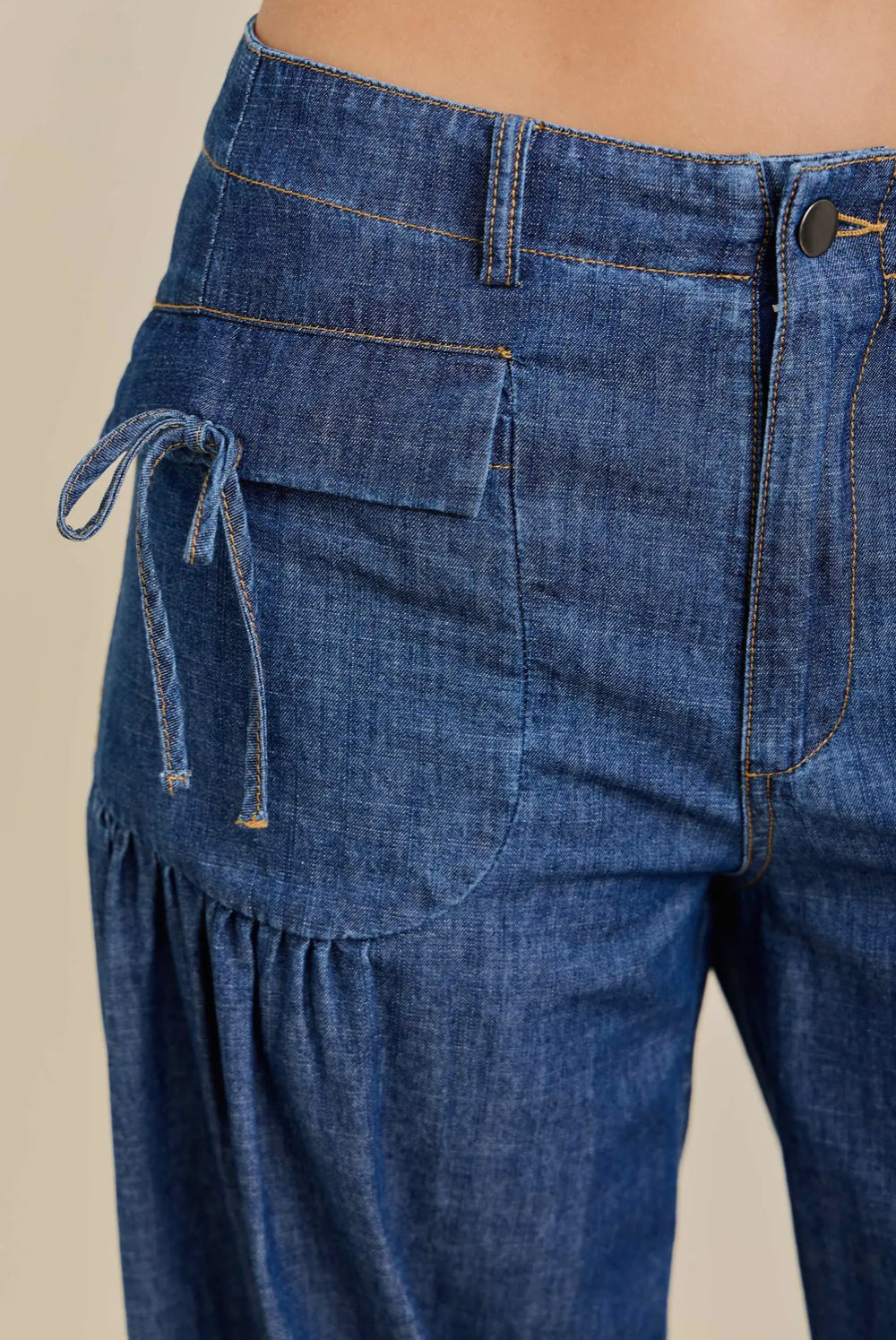Blue denim wide-leg cinched jogger with front zipper, button, flap pocket, side tie; sizes XS-L.