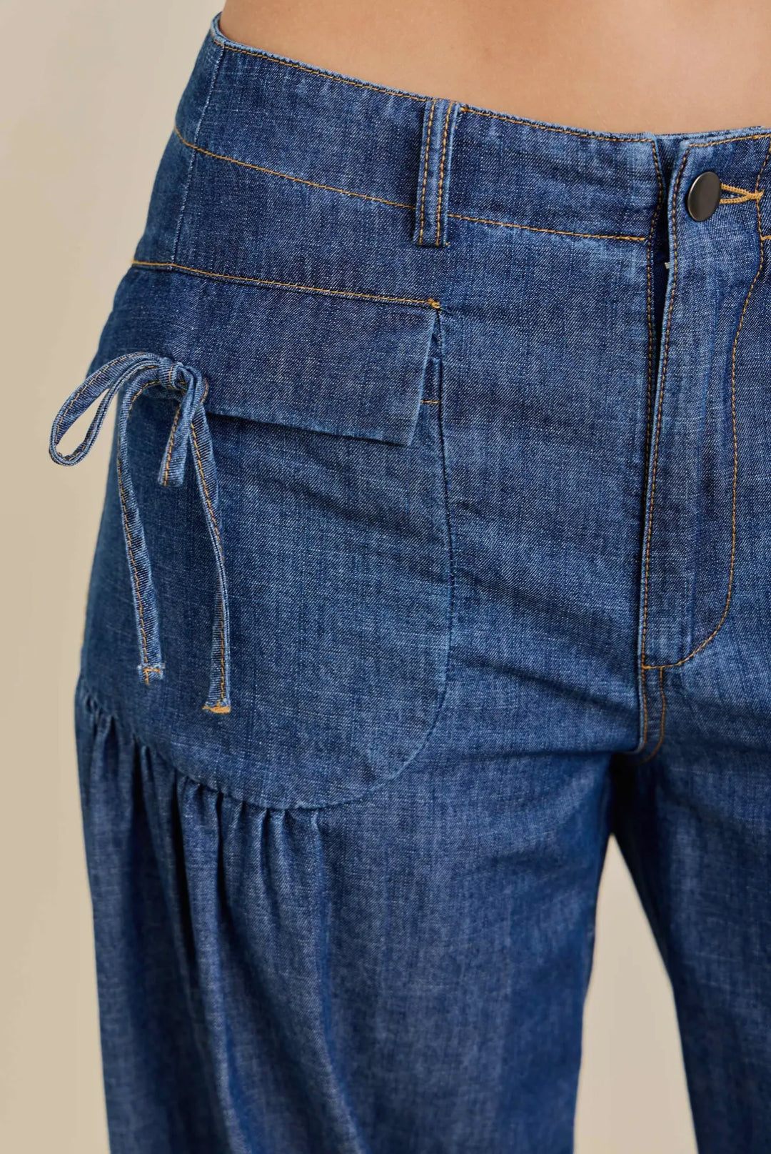 Blue denim wide-leg cinched jogger with front zipper, button, flap pocket, side tie; sizes XS-L.