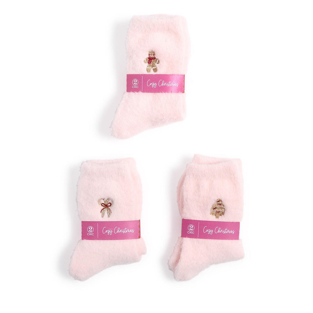 Three pairs of pink Cozy Holiday Socks with embroidered holiday icons and branded paper bands.