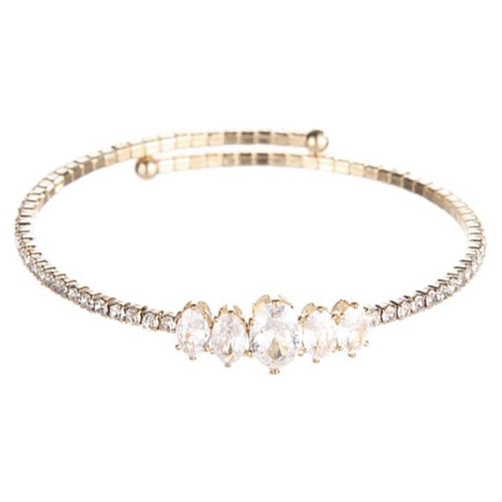 Slim gold bangle with five large oval clear gemstones, baguette and round crystal accents. Available in S, M, L.