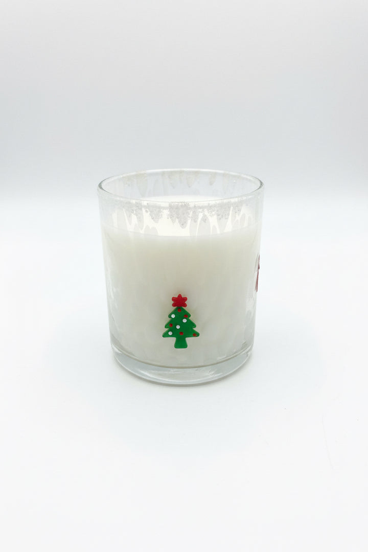 The Holiday Soy Candle features white soy wax in a glass holder decorated with a small green Christmas tree and a red star. Available in multiple sizes.