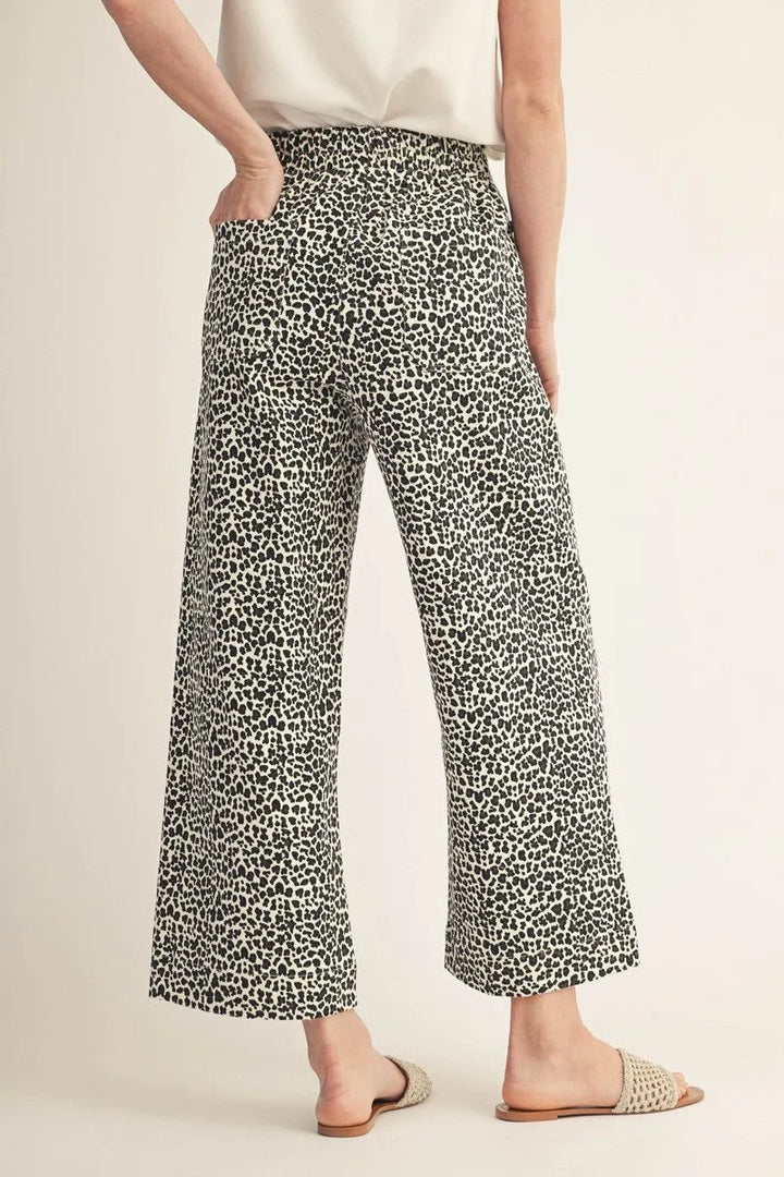 Ivory high-waisted jeans with black animal print, side pockets, and scalloped hem. Available in multiple sizes.