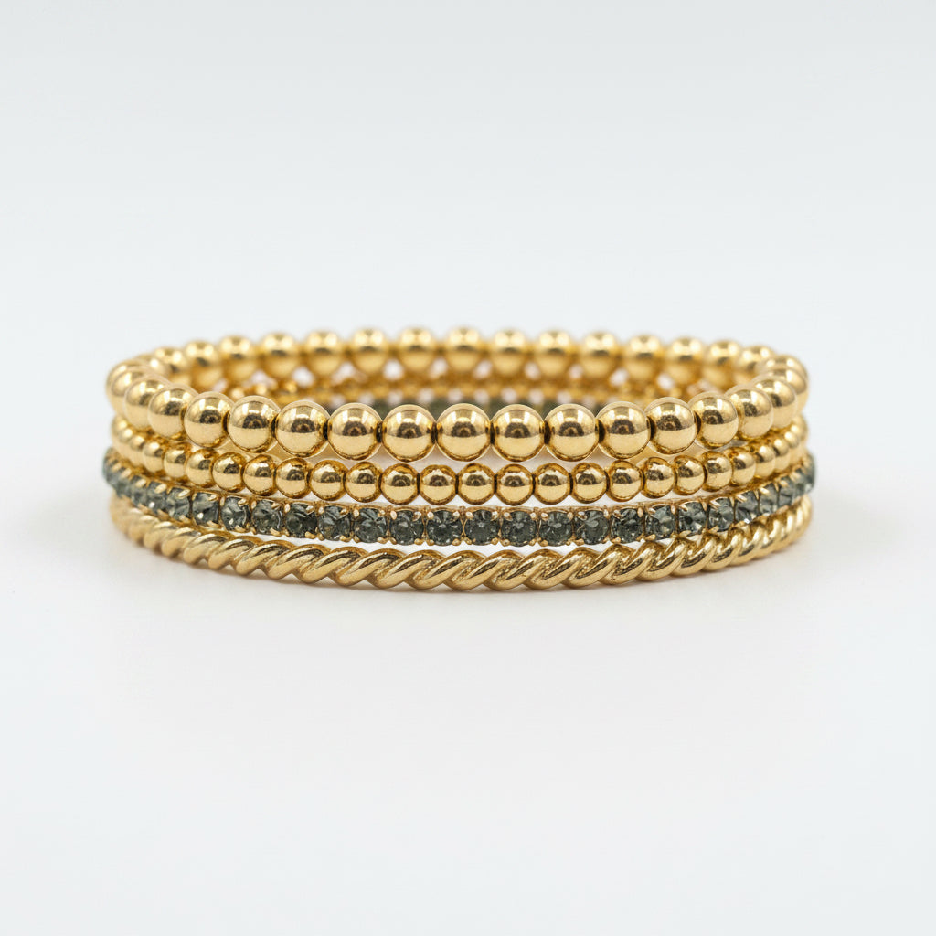 Logan Multi Strand Bracelet Stack: four gold bracelets—three with beads, one twisted rope, and one with small blue inlaid stones. Available sizes: S, M, L.