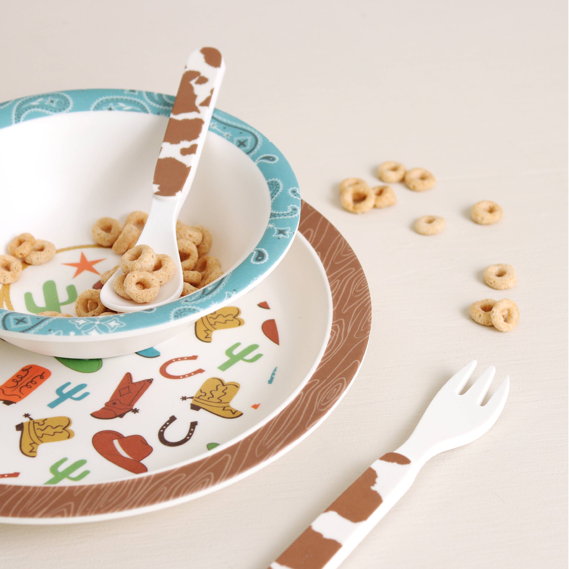 Itzy Bistro™ 4-Piece melamine, BPA-free set: cowboy bowl, plate, cow-print spoon and fork. Available in toddler sizes.