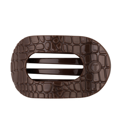 The Brown Crocodile Large Flat Round Hair Clip is a dark brown, oval accessory with a crocodile skin texture, two solid center bars, and a flat back for secure wear. Available in large size.