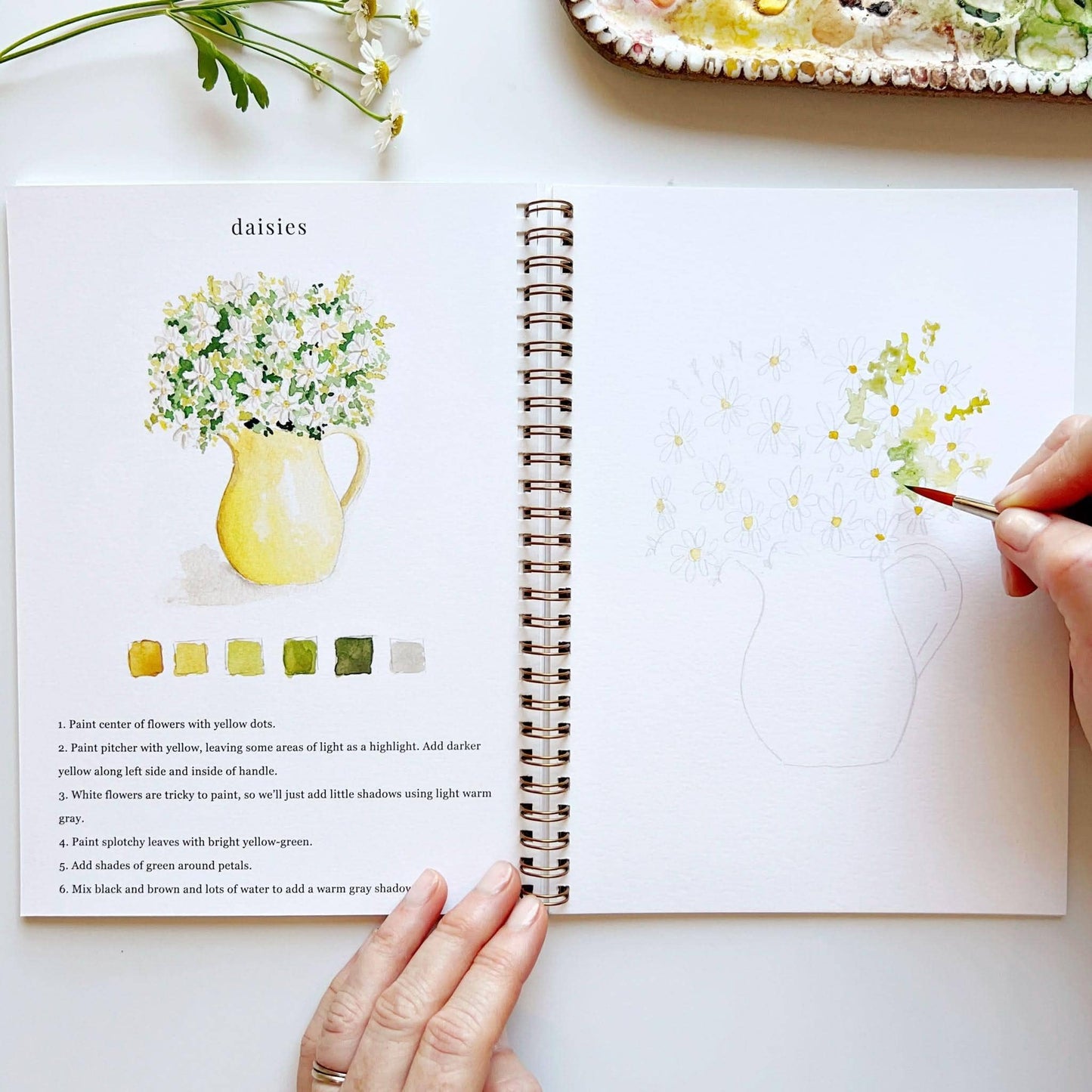 The Flowers Watercolor Workbook is open to daisy tutorials and finished art. Available in standard workbook sizes.