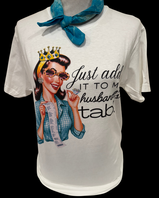 White crew t-shirt, "Husband's Tab," available in size L. Features a pin-up style crowned woman in sunglasses holding an oversized receipt, sparkling Swarovski stone details, and the phrase “Just add it to my husband’s tab!”.