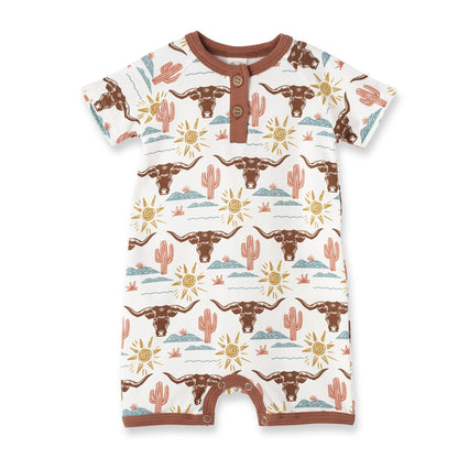 Western baby romper with brown steer heads, cacti, sun, and clouds; brown trim, chest buttons, leg snaps. Sizes NB-24M.