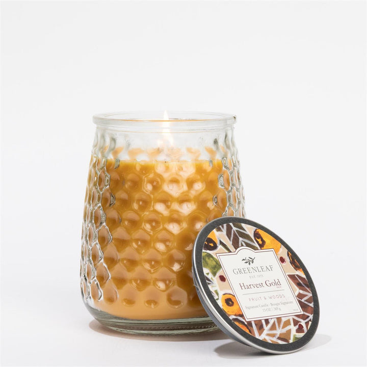 Lit Harvest Gold Signature Candle, 13 oz, in textured glass jar; available in additional sizes.