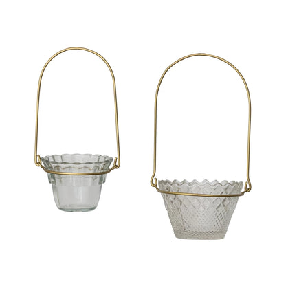 Two pressed glass votive holders with scalloped edges, textured patterns, and antique brass handles. Available in two sizes.
