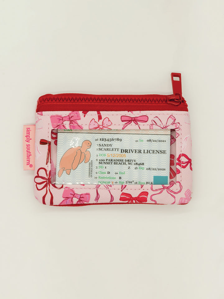 Pink Key Chain Wallet with red zipper, bow pattern, zip pockets, clear ID window. "Simply Southern" tag. Sizes: S, M, L.