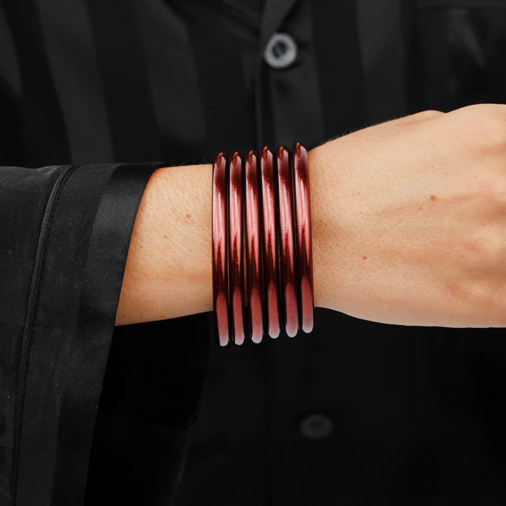 Five shiny Merlot All Weather Bangles stacked; available in small, medium, large.
