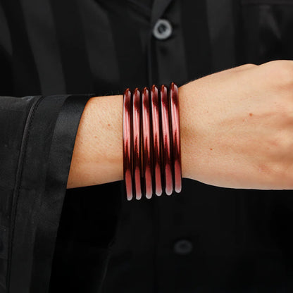 Five shiny Merlot All Weather Bangles stacked; available in small, medium, large.