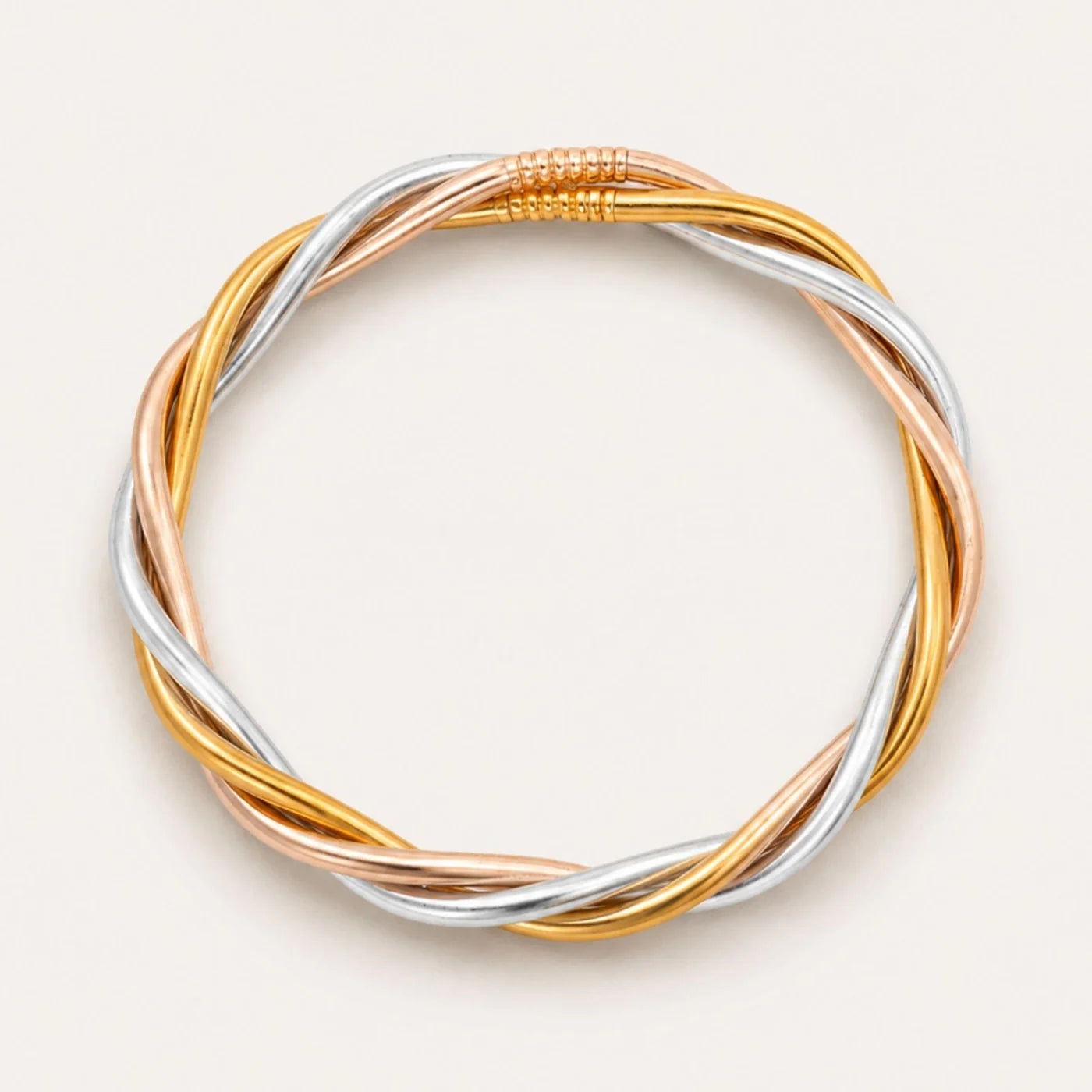 Trilogy All Weather Bangle featuring twisted, interwoven strands of gold, silver, and rose gold with a seamless circular design and coiled accent at the top; available in multiple sizes.