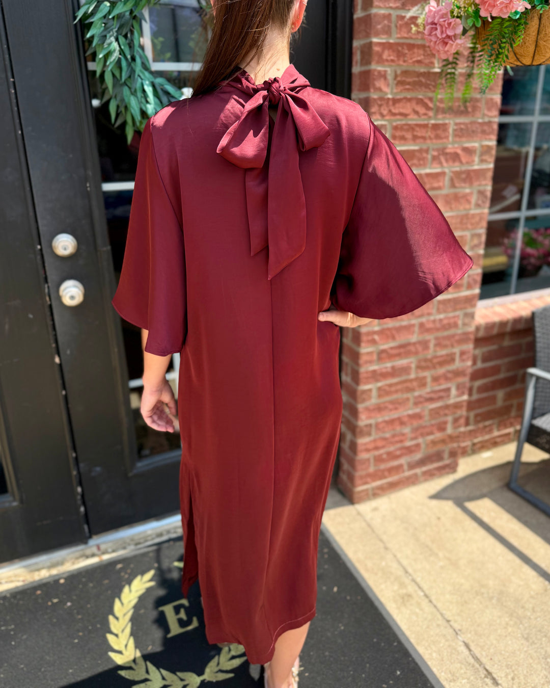 Burgundy Satin Tie Back Midi Dress with wide sleeves and an elegant bow at the nape of the neck. Available in sizes XS–XL.