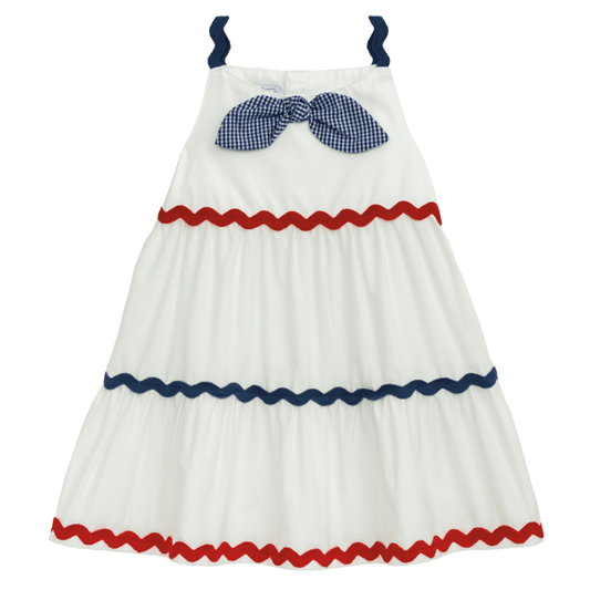 Sleeveless white dress with navy straps, blue gingham bow, red/navy ric rac trim. Sizes: 2T-6X.